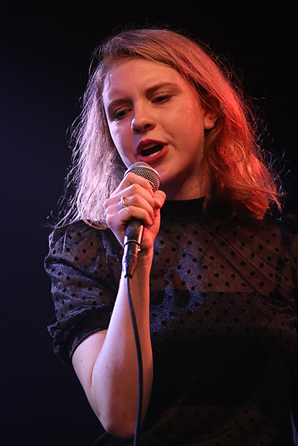 Zangeres zingt met microfoon in de hand op het podium